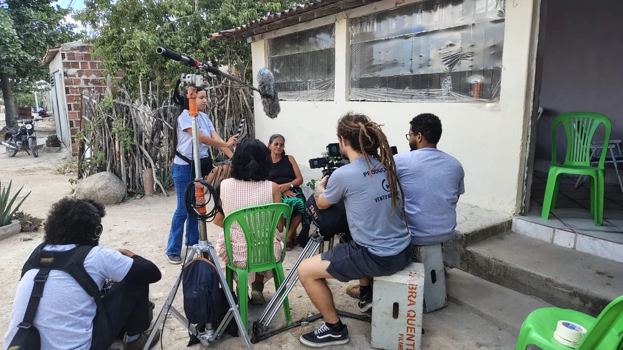 Equipe registra uma entrevista com uma moradora diante de sua casa.